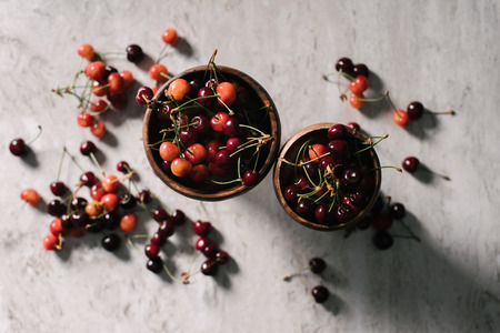 top view of fresh ripe healthy cherries in bowls on marble surface