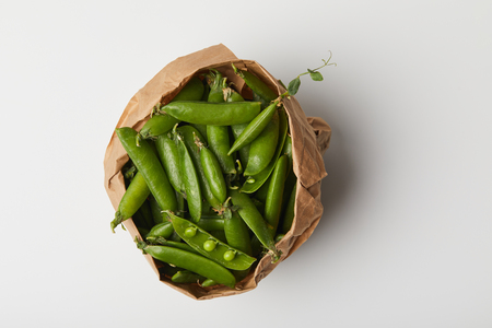 top view of pea pods in paper bag on white surfaceの写真素材
