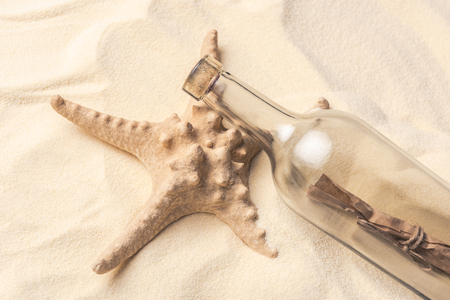 Starfish and bottle with letter on light sandの写真素材