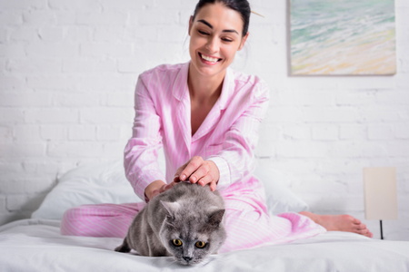 happy woman with britain shorthair cat resting on bed at homeの写真素材