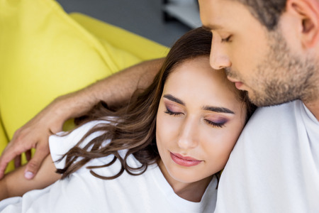 close-up view of beautiful happy young couple with closed eyes embracing at home