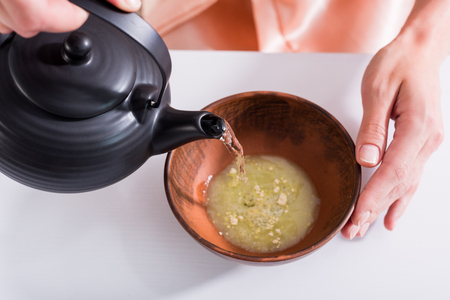 cropped shot of woman making tea while having tea ceremony in morning at homeの写真素材