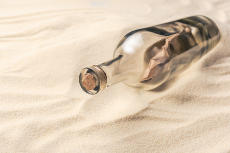 Corked bottle with message on sandy beachの写真素材