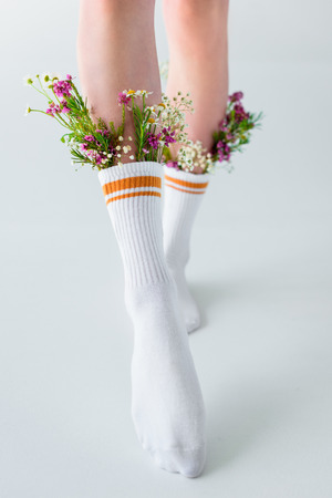 cropped shot of girl in socks with beautiful flowers walking isolated on greyの写真素材