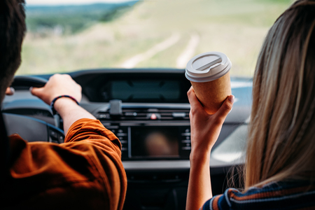 partial view of man driving car while his girlfriend sitting near with paper cup of coffeeの写真素材