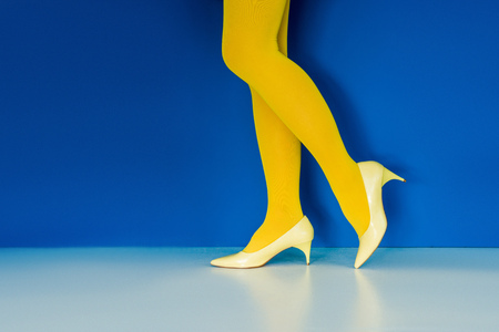 Cropped view of girl in yellow shoes and pantyhose on blue backgroundの写真素材