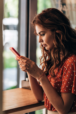 side view of young woman using smartphone in cafeの写真素材