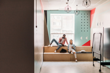 young students sitting on wooden tribunes at collegeの写真素材