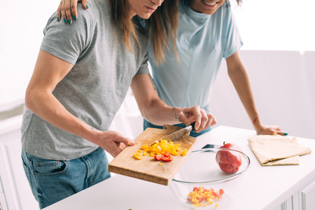cropped image of woman embracing boyfriend while he cooking at kitchenの写真素材