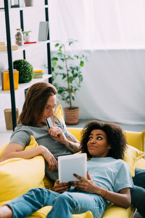 interracial couple doing online shopping with credit card and digital tabletの写真素材