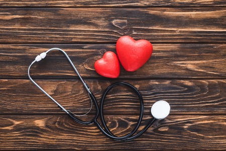 top view of stethoscope and red hearts symbol on wooden tableの写真素材