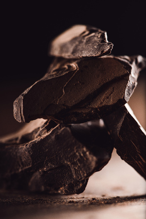closeup shot of arranged pieces of dark chocolate on wooden table on black backgroundの写真素材