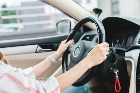 partial view of woman with hands on steering wheel driving car