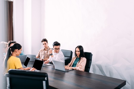 multicultural business partners having meeting at table with laptops in modern officeの写真素材
