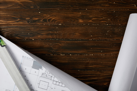 top view of spirit level and blueprint on wooden brown table