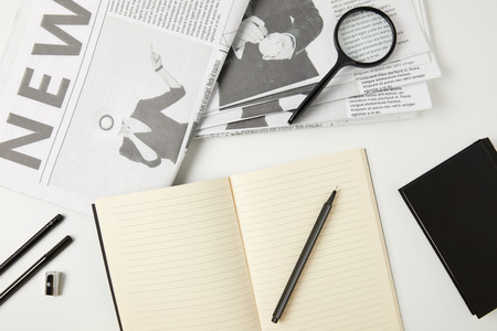 top view of notebooks, newspapers, office supplies and magnifying glass on greyの写真素材