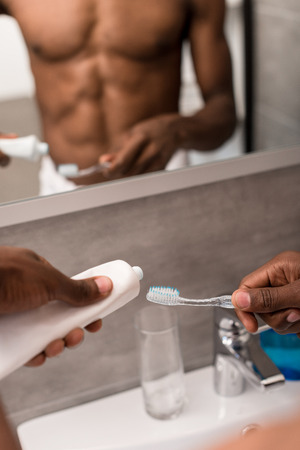 cropped shot of man applying toothpaste onto brush in front of mirrorの写真素材