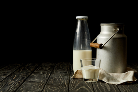 milk in bottle, glass and aluminium can on sackcloth on black backgroundの写真素材
