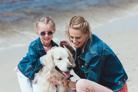 smiling family with golden retriever dog on sea shoreの写真素材