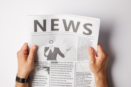 cropped view of man holding and reading daily newspaperの写真素材