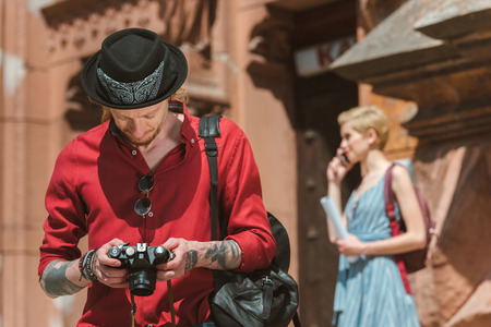 man looking at photo camera while girlfriend standing behindの写真素材
