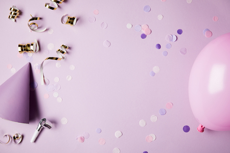top view of confetti pieces, balloon and party hat on violet surfaceの写真素材