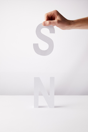 cropped view of person holding paper letters - n and s, on white backgroundの写真素材