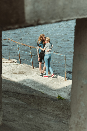 tattooed boyfriend and stylish girlfriend hugging on bridge near riverの写真素材