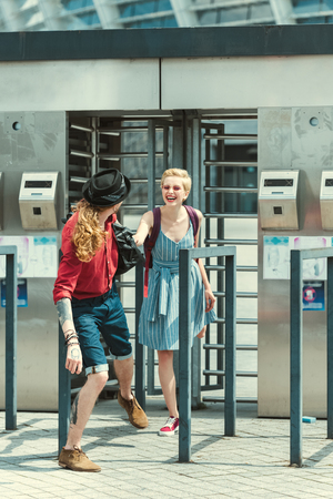 cheerful couple of tourists holding hands on station of public transport in cityの写真素材