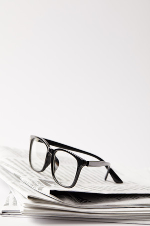 close up of newspapers with black eyeglasses, on white with copy spaceの写真素材