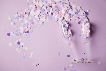 top view of confetti pieces and empty glasses on surfaceの写真素材