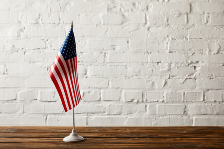 united states of america flagpole on wooden surface against brick wallの写真素材