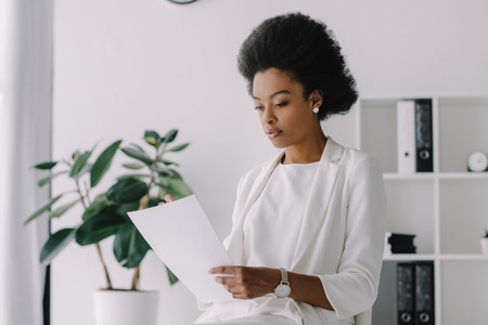 attractive african american businesswoman reading document in officeの写真素材