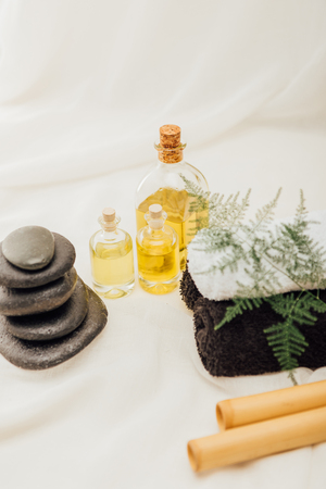 close up view of arrangement of spa treatment accessories with towels, pebbles and essential oil on white backgroundの写真素材