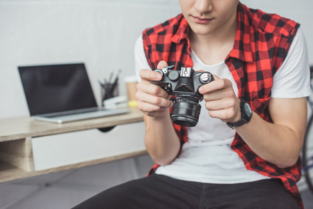 cropped view of teenager with retro film camera sitting at homeの写真素材
