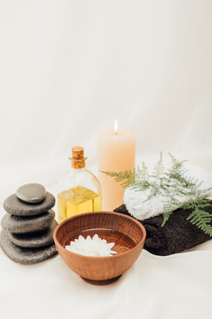 arrangement of spa treatment accessories and chrysanthemum flower in wooden bowl on white backgroundの写真素材