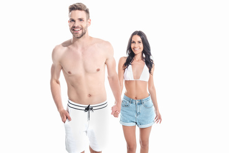 beautiful smiling couple in swimwear holding hands, isolated on whiteの写真素材