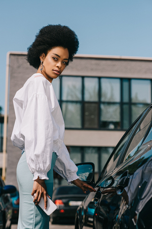 attractive african american businesswoman opening car on parkingの写真素材