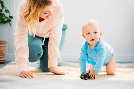 mother and child crawling together on carpet at homeの写真素材