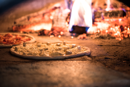 close up view of italian pizza baking in brick oven in restaurantの写真素材