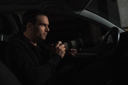 side view of male paparazzi spying by camera with lens from his carの写真素材