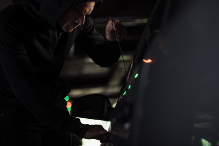 male thief in black hoodie intruding car by picklockの写真素材