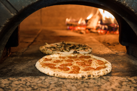 close up view of italian pizza baking in brick oven in restaurantの写真素材