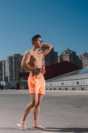 handsome young shirtless man with cocktail on parkingの写真素材
