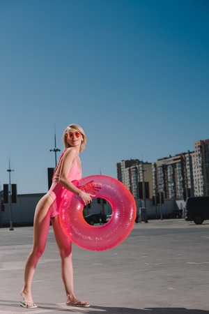 happy young woman in swimsuit with inflatable ring on parkingの写真素材