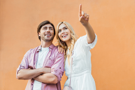 portrait of young stylish couple standing against city building wallの写真素材