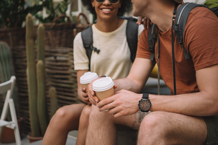 cropped image of couple sitting with disposable cups of coffeeの写真素材