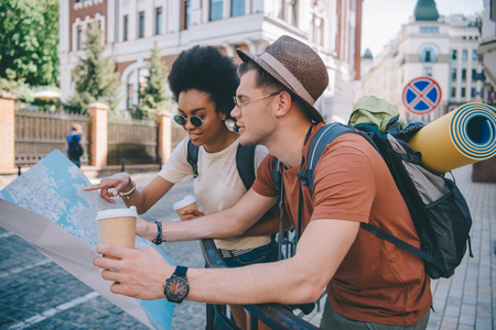 multiethnic couple of young tourists with map and coffee cupsの写真素材