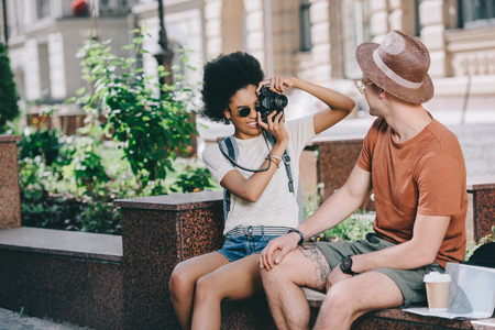 young female traveler taking picture of boyfriend on camera