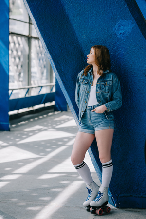 pensive stylish woman in denim clothes, high socks and retro roller skates looking awayの写真素材